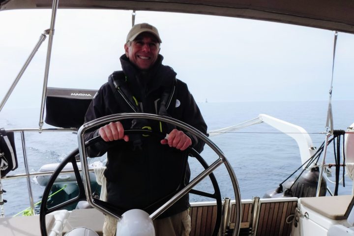 a man standing in front of a boat next to a body of water