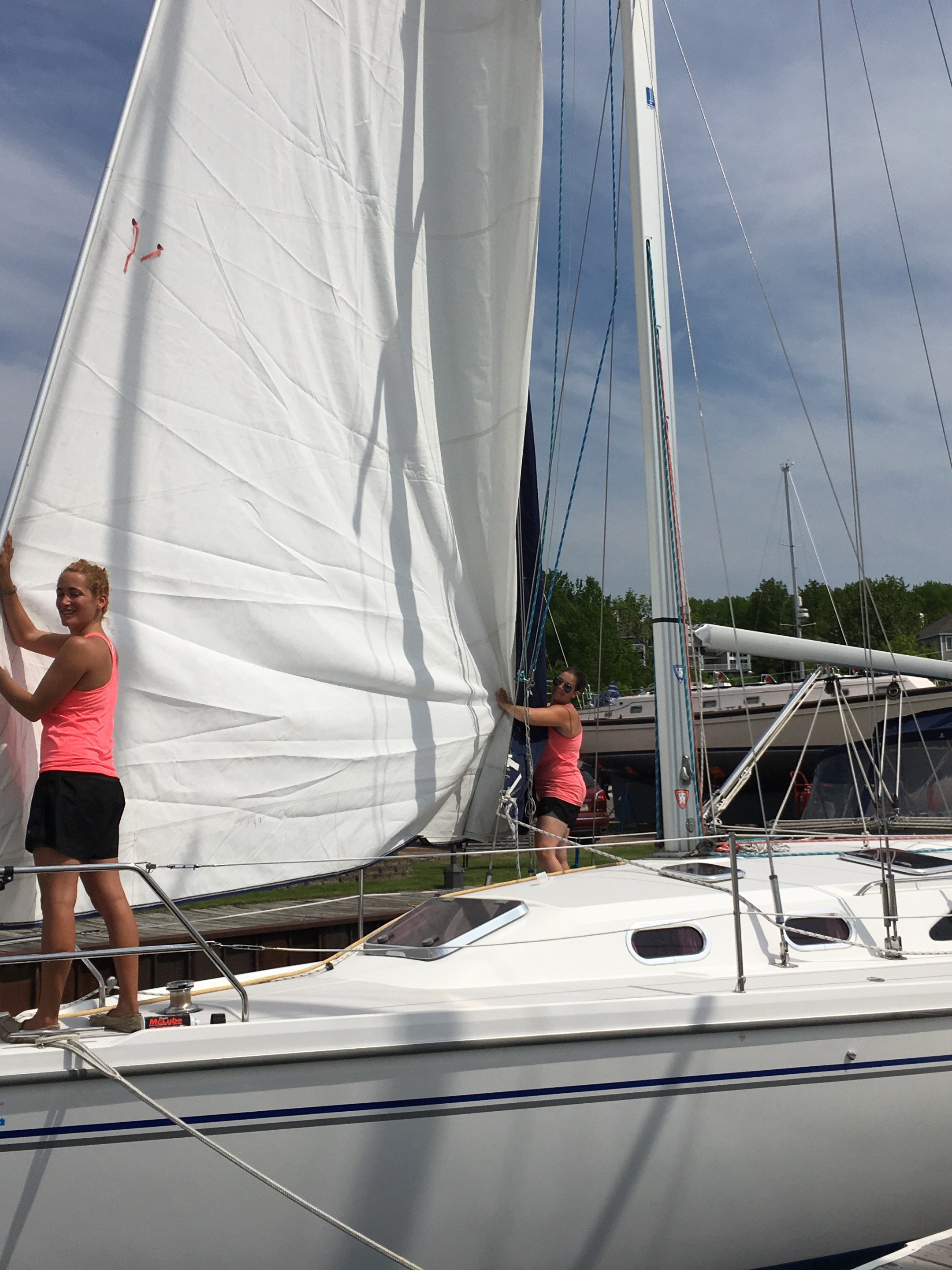 Crew members standing on sailboat hoisting sails