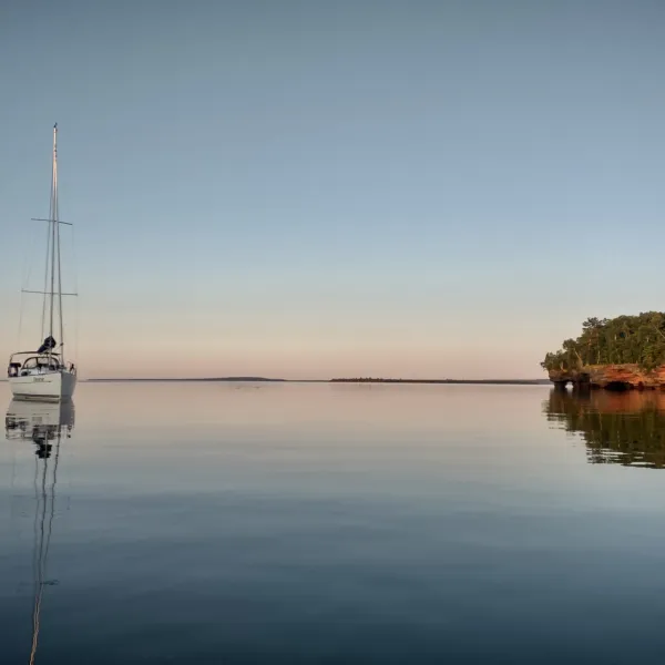 a boat floating along a river next to a body of water