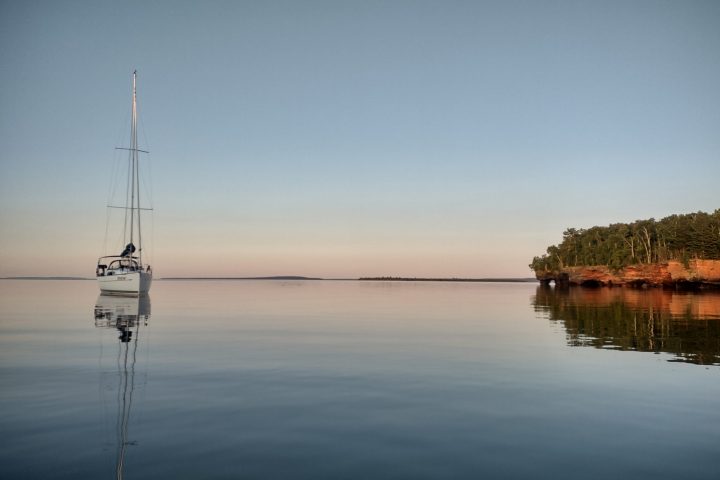 a boat floating along a river next to a body of water