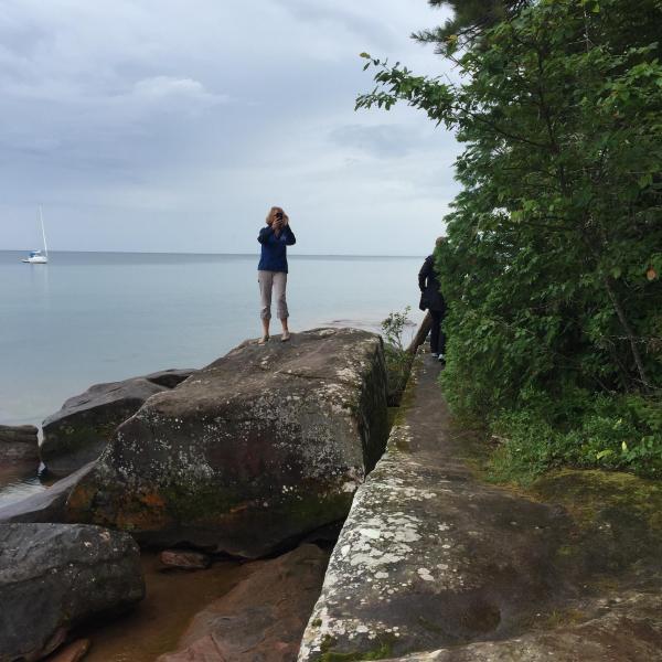 Women standing on lake beach looking out to the water
