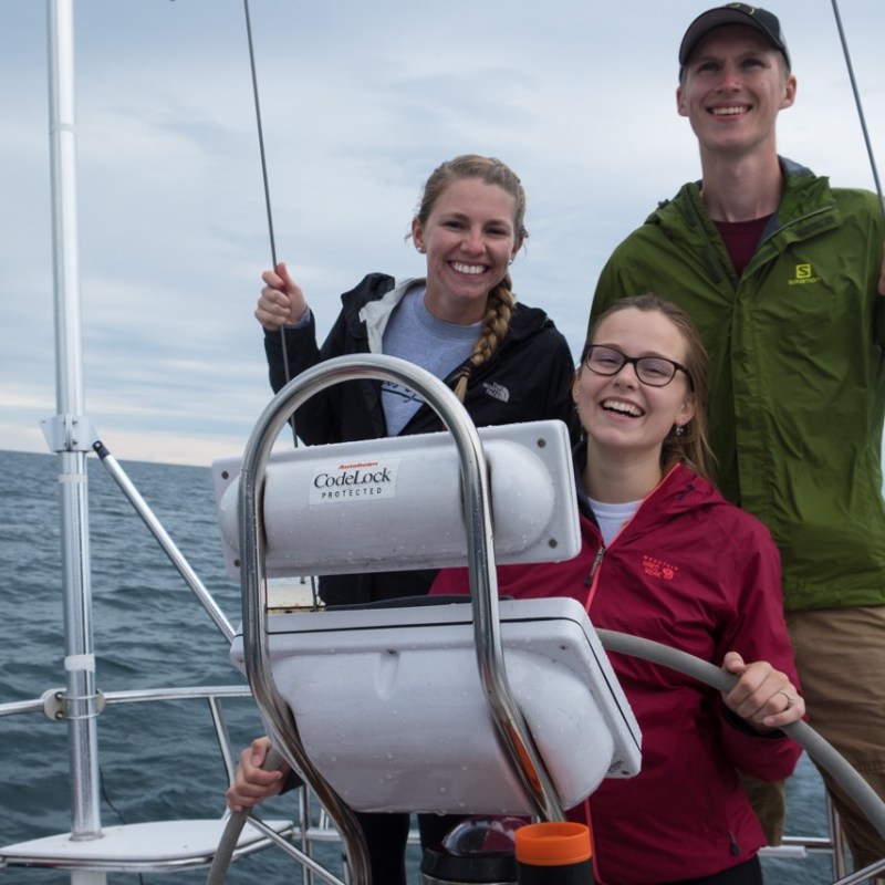 Family standing near sailboat steering wheel