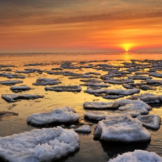 Ice blocks floating on lake during sunset