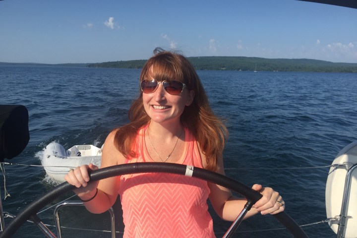 Women steering sailboat and smiling