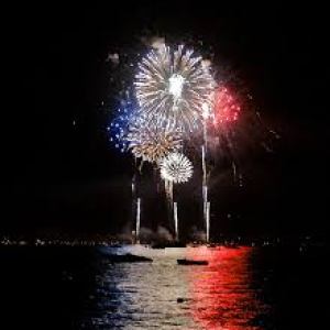 Fireworks shooting up in the night sky above a lake