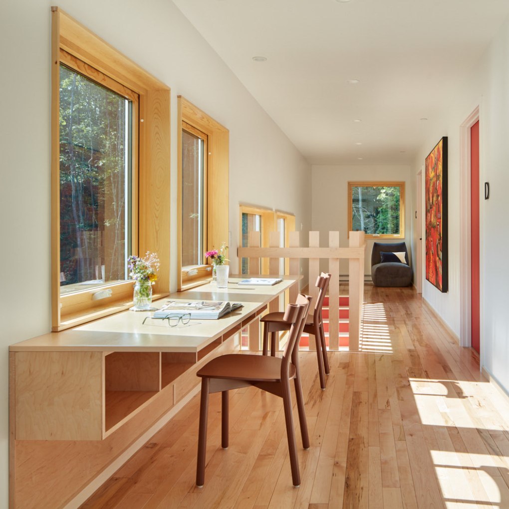 Bright hallway with wooden desks, chairs, and large windows.